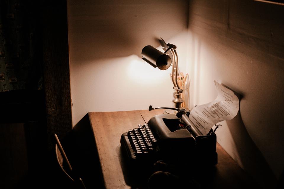 Máquina de escrever sob a luz de uma luminária, com papel datilografado