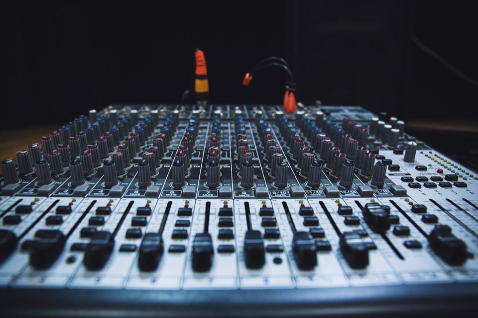 Mesa de mixagem de áudio com faders no escuro