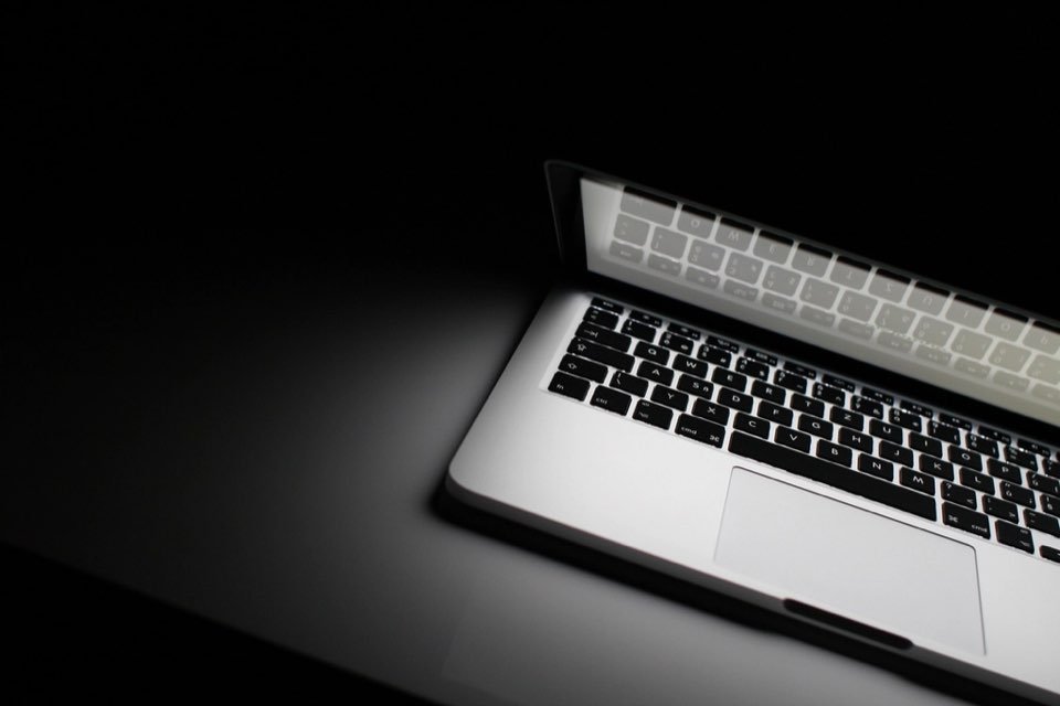 Teclado de laptop iluminado sobre mesa escura