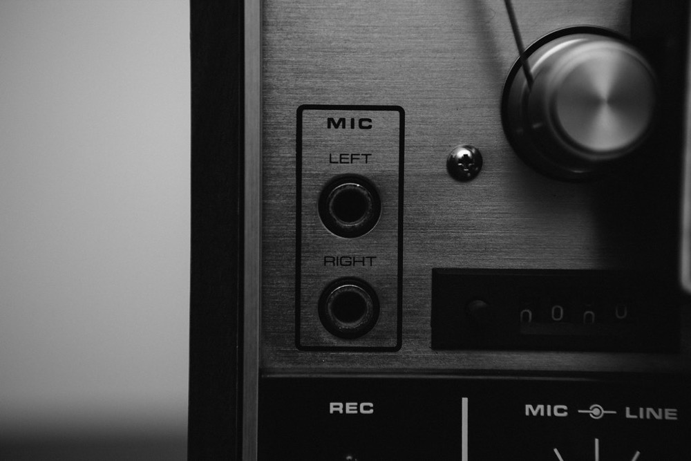 Painel de gravador de audio antigo em preto e branco, com entradas de microfone esquerda e direita e o botao REC