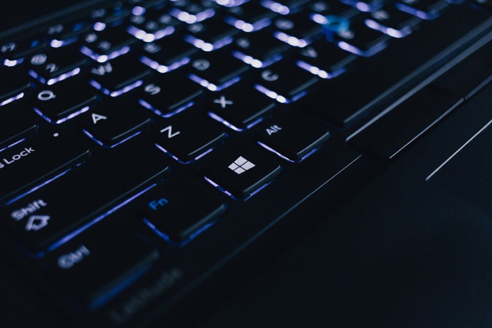 Teclado de notebook com retroiluminacao azul e tecla Windows em destaque no escuro