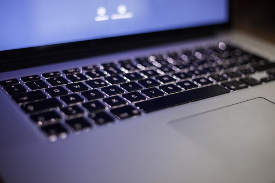 Teclado de laptop retroiluminado em azul sobre fundo escuro