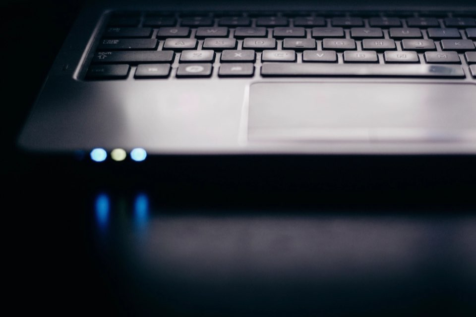 Teclado de laptop com luzes azuis no escuro
