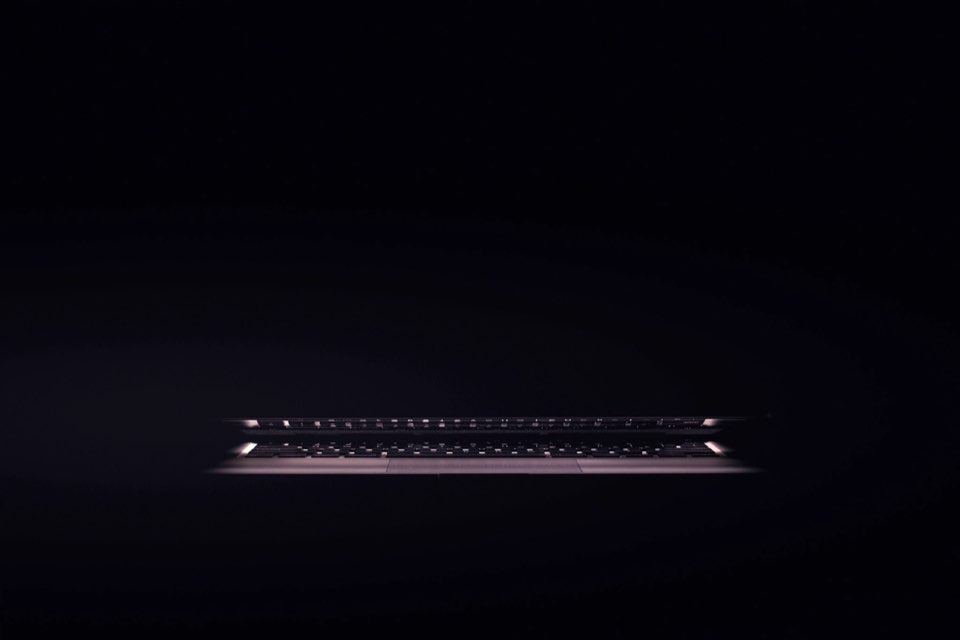 Laptop entreaberto iluminado pelo teclado em ambiente completamente escuro